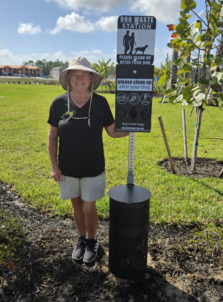 Kate, owner of Scoops of SWFL, standing beside a dog waste station